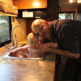 Eltern mit Baby im gemütlichen Wohnmobil während der Elternzeit